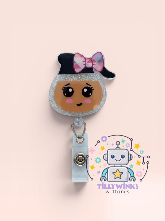 A cute cartoon robot with a bow on its head, and a badge clip attached to it, against a light pink background.