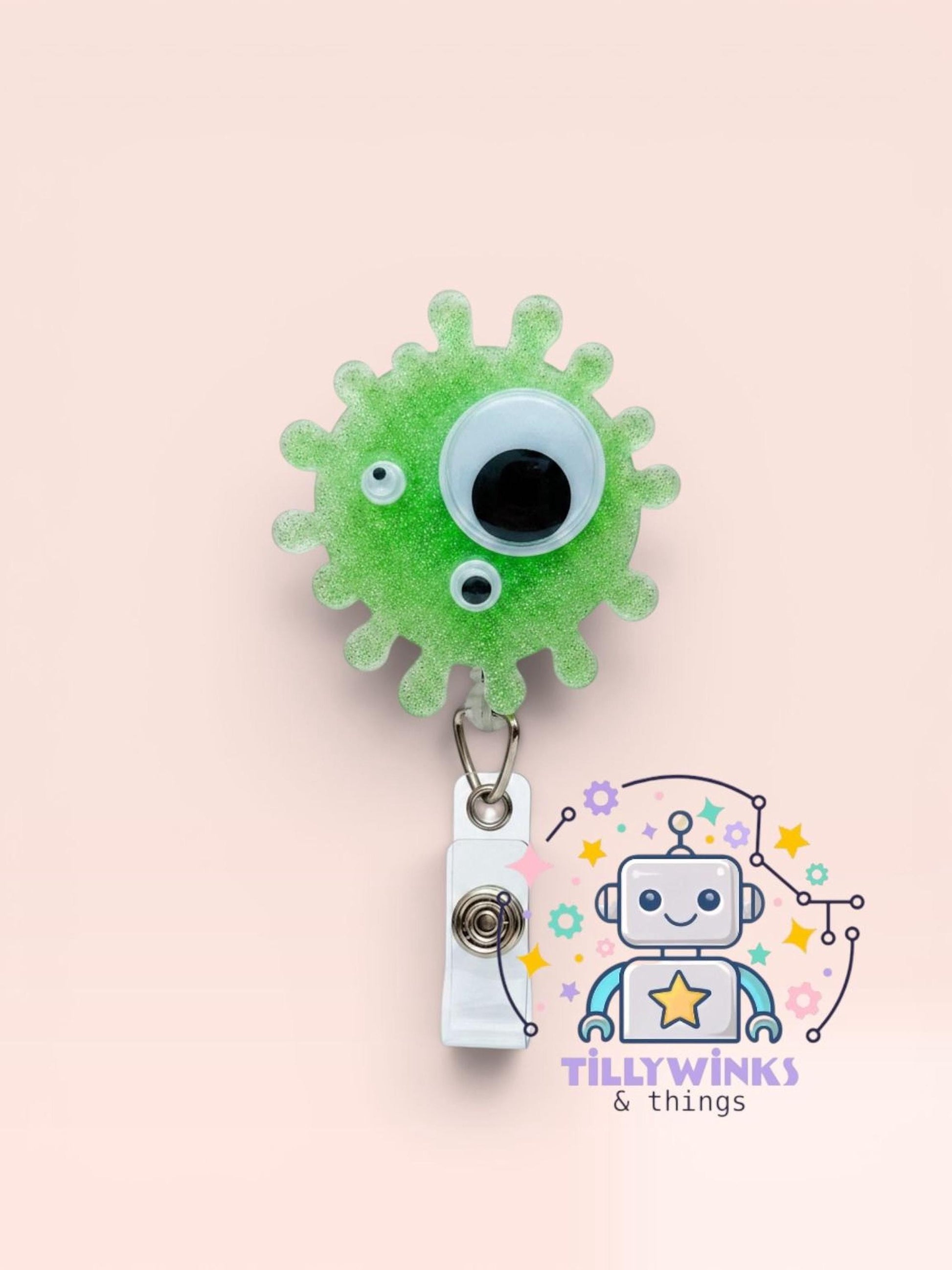 a green glittery robot-shaped badge holder with a white tag attached to it, and a robot-themed logo for a business called "Tillywinks & things".