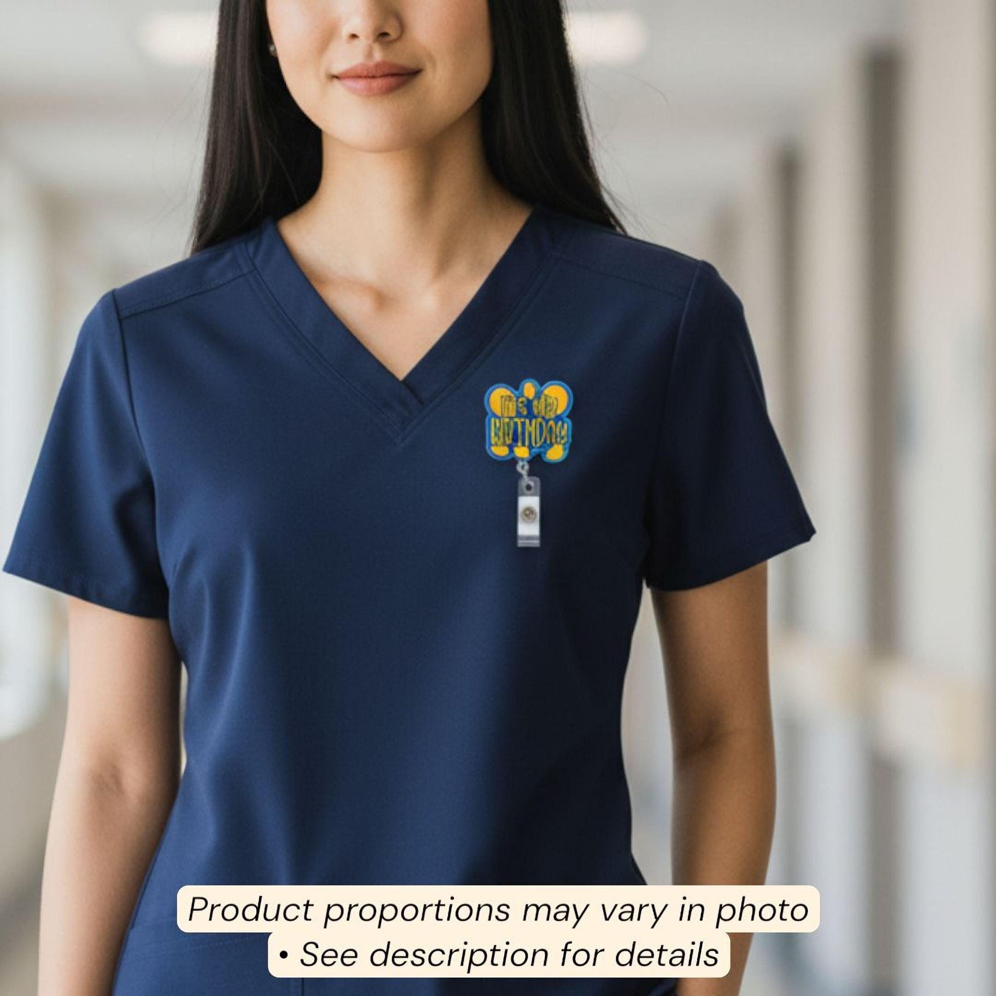 A woman wearing a blue nursing uniform with a badge on the left side of her chest.
