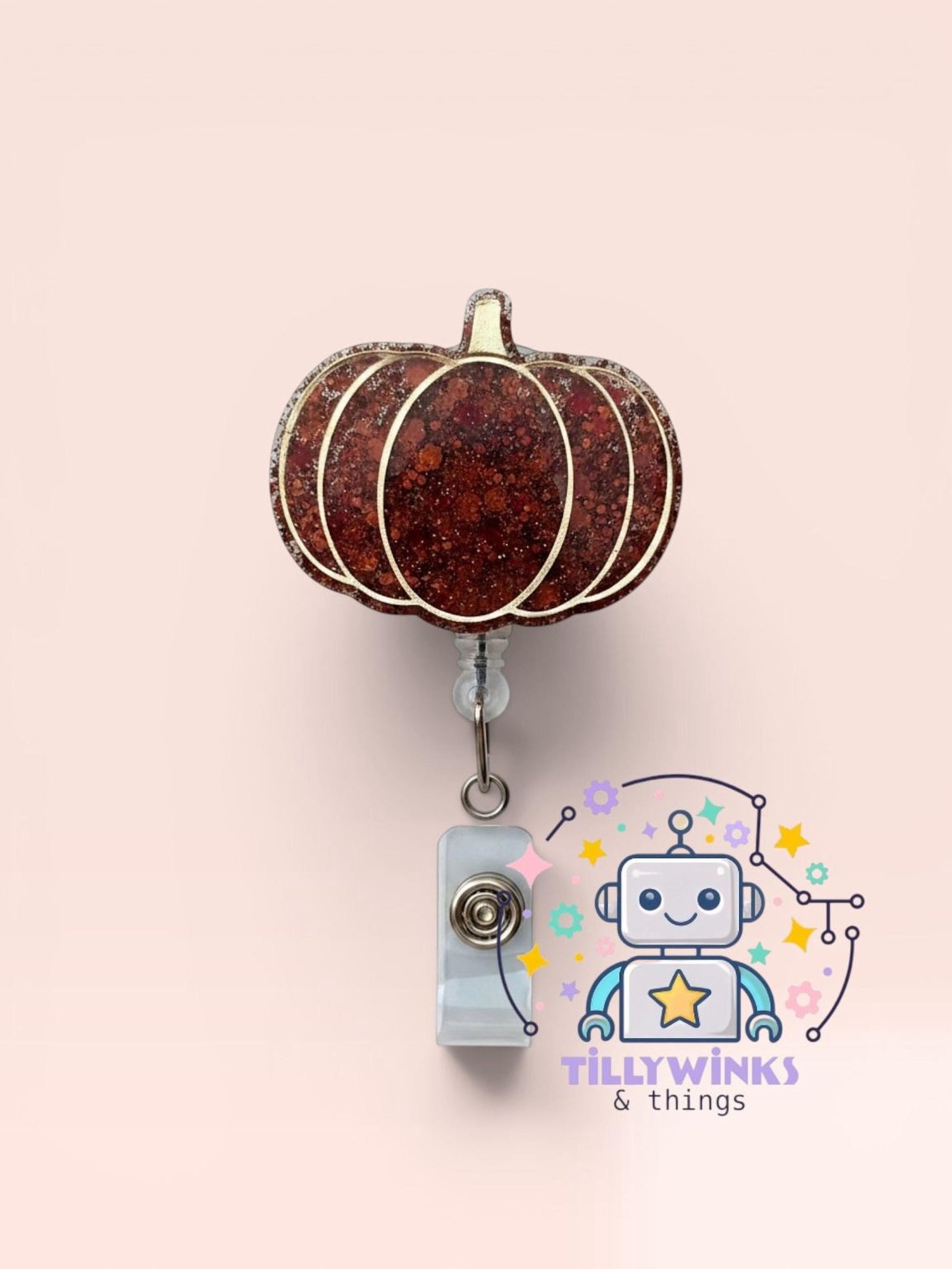 a brown glittery pumpkin-shaped badge with a silver chain hanging from it, and a robot-like character with a star on its face in the background.