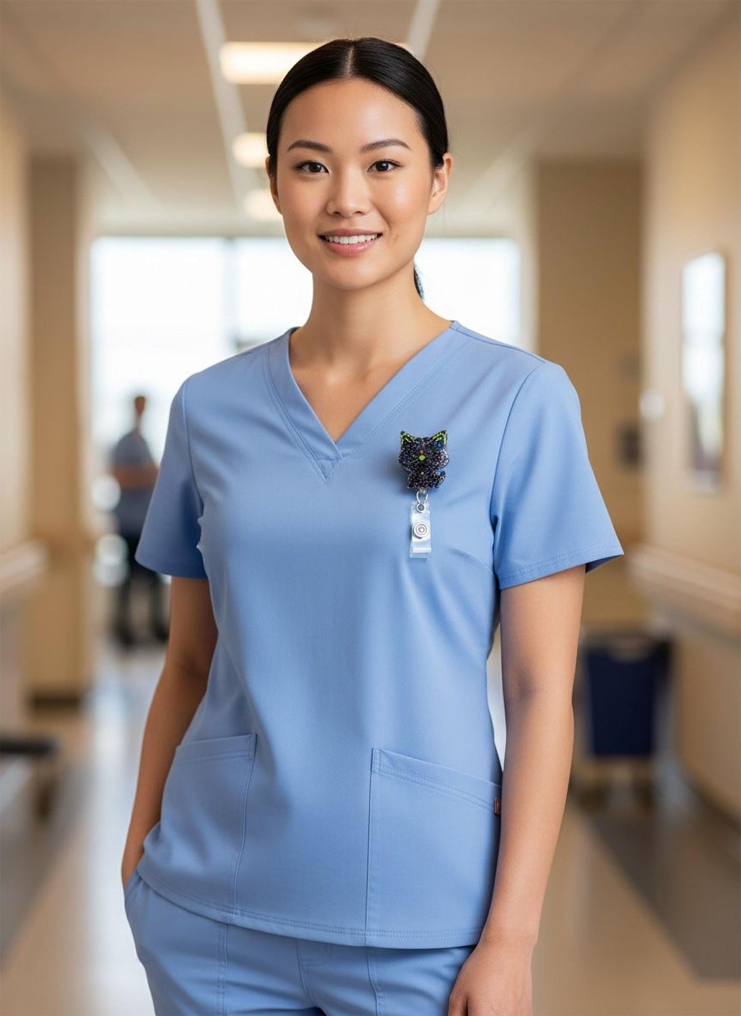 A smiling woman wearing a blue medical uniform with a badge on the left side of her chest.