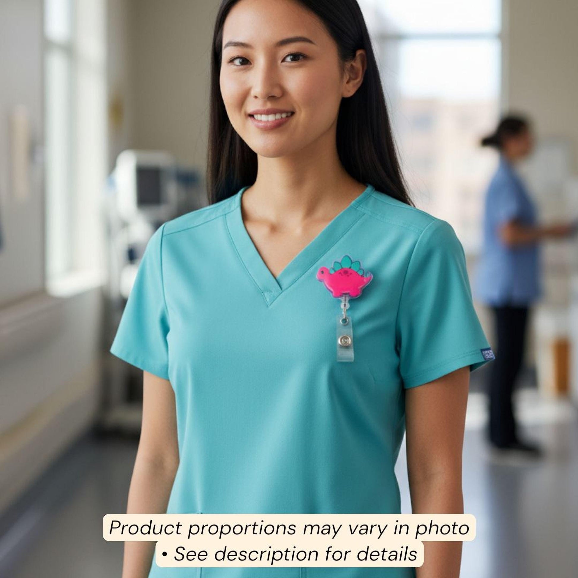 A smiling woman wearing a turquoise medical uniform with a pink badge on the left side of her chest.