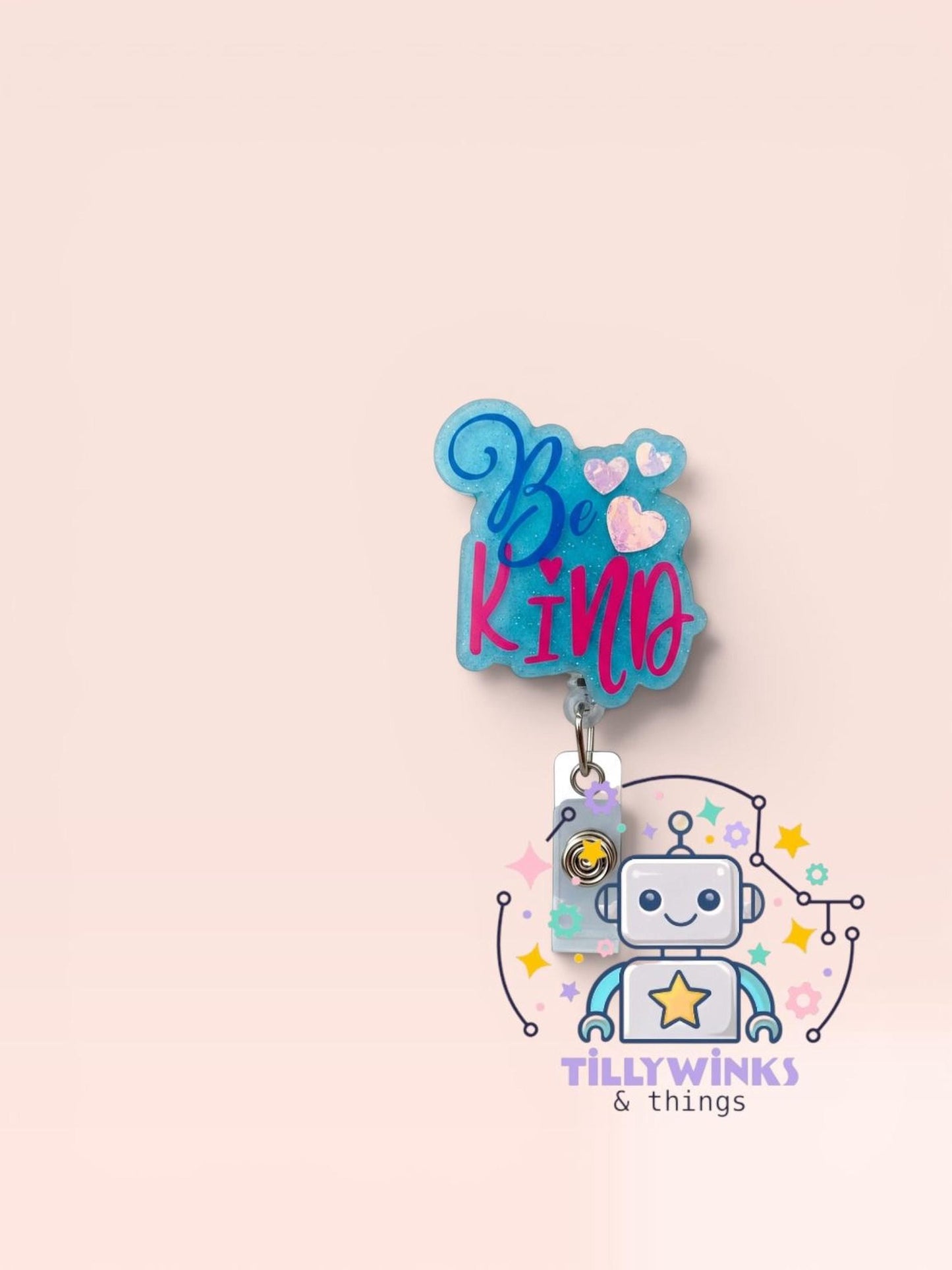 a robot with a heart-shaped charm attached to it, along with a keychain-like charm. The charm has the text "Be kind" written on it.