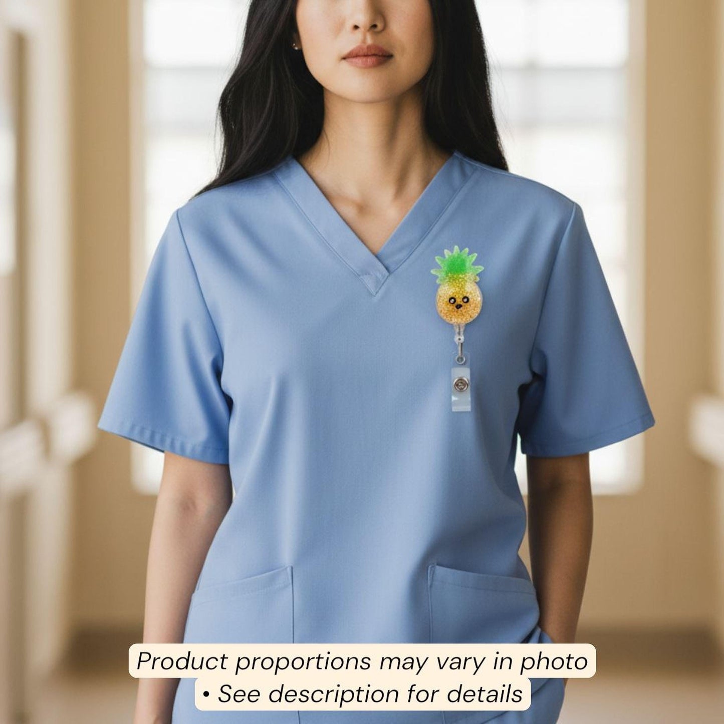 A woman wearing a blue medical scrubs top with a pineapple-shaped badge on the left side of her chest.