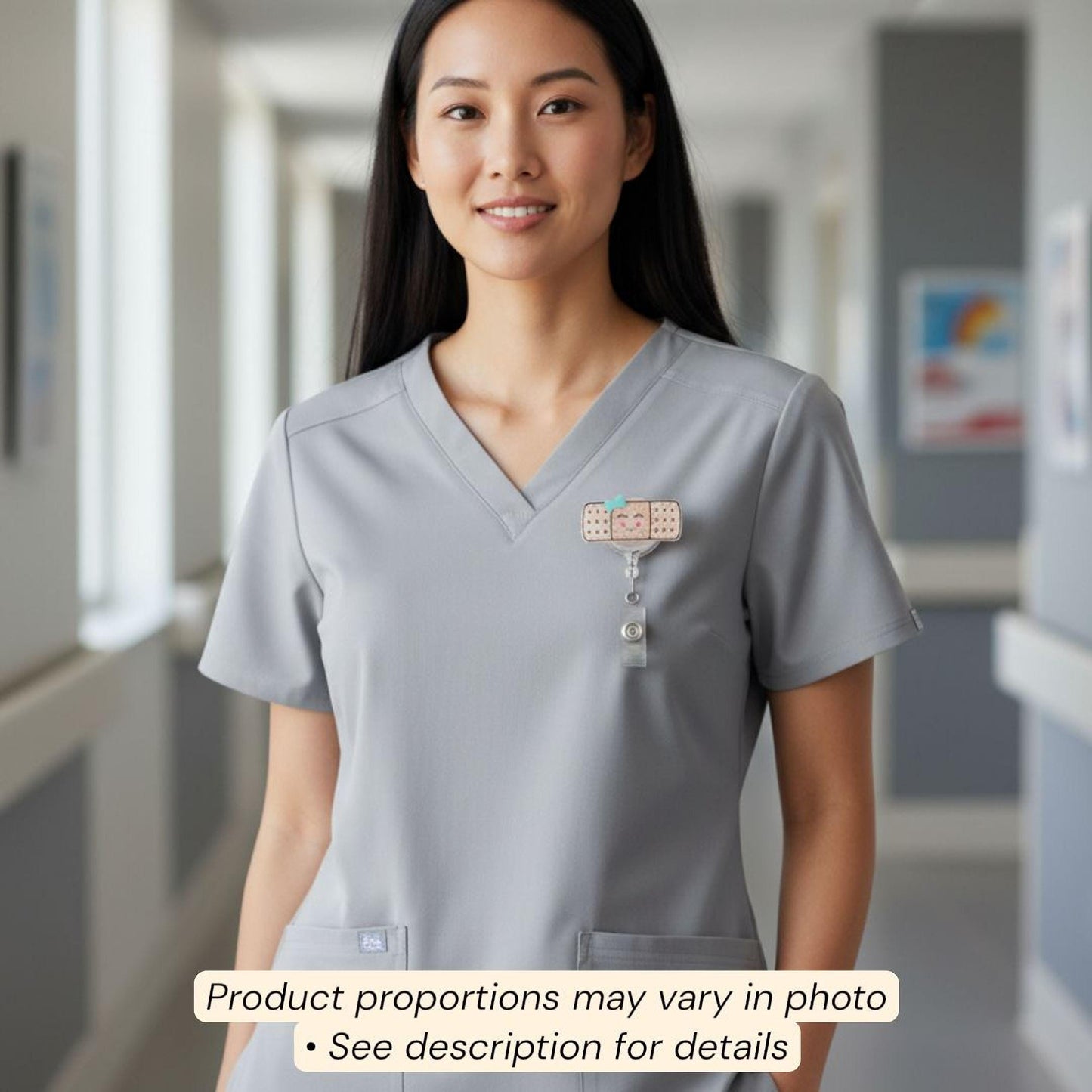A smiling woman wearing a gray medical uniform with a badge on her shirt, standing in a hallway.