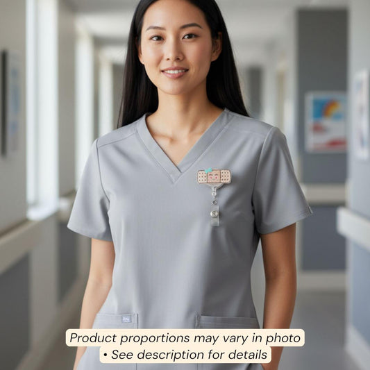 A smiling woman wearing a gray medical uniform with a badge on her shirt, standing in a hallway.