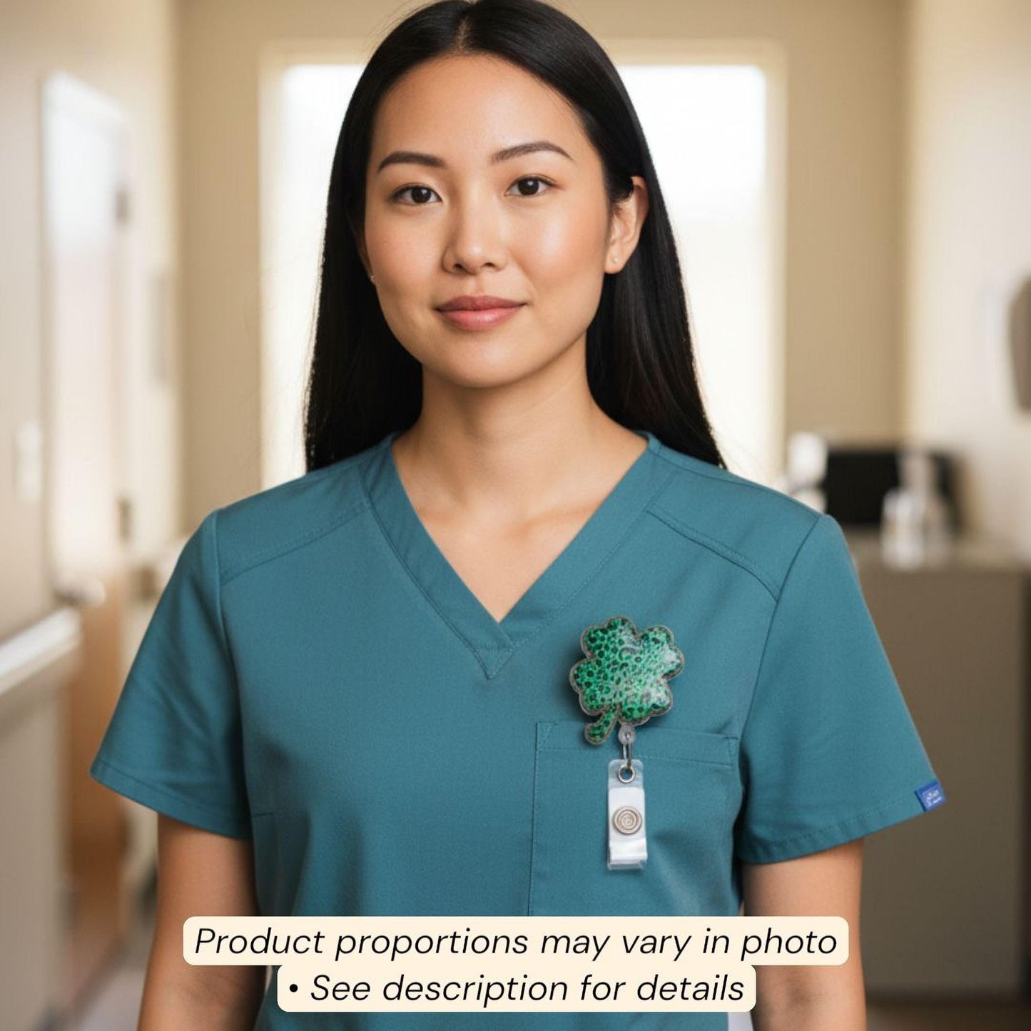 A woman wearing a teal-colored nursing uniform with a green clover pin on her left breast pocket.