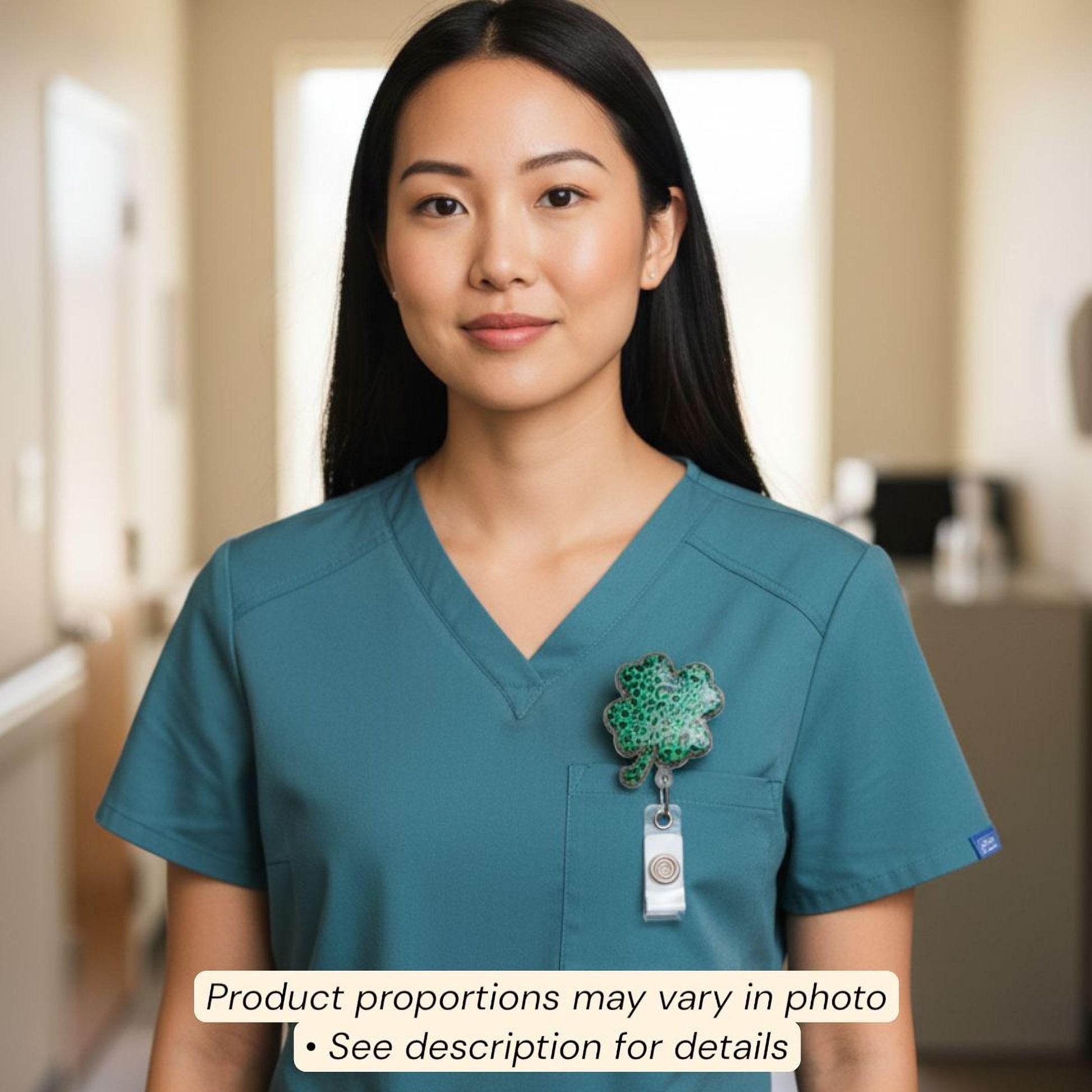 A woman wearing a teal-colored nursing uniform with a green clover pin on her left breast pocket.