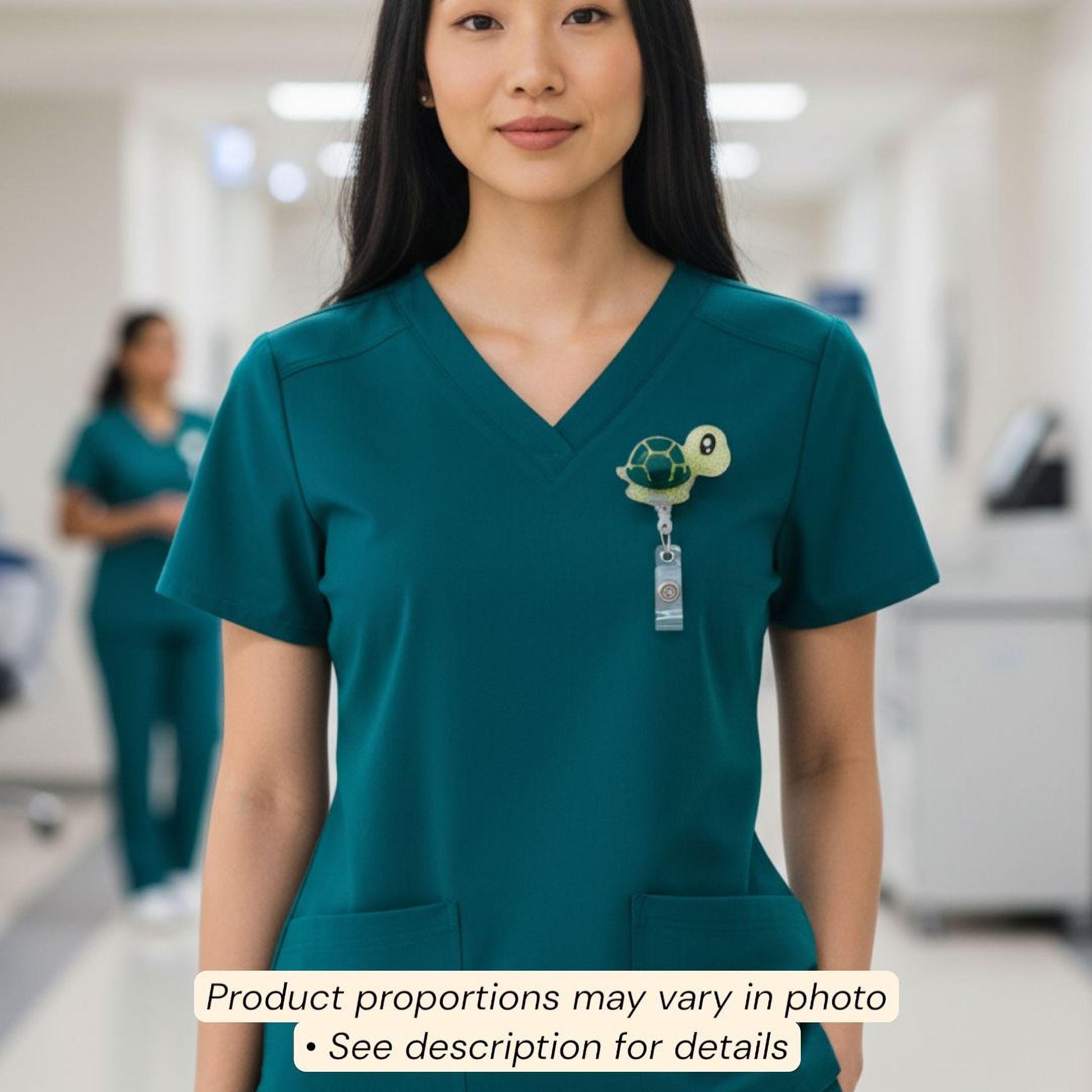 A woman wearing a teal-colored medical uniform with a turtle-shaped badge on the left side of her chest.