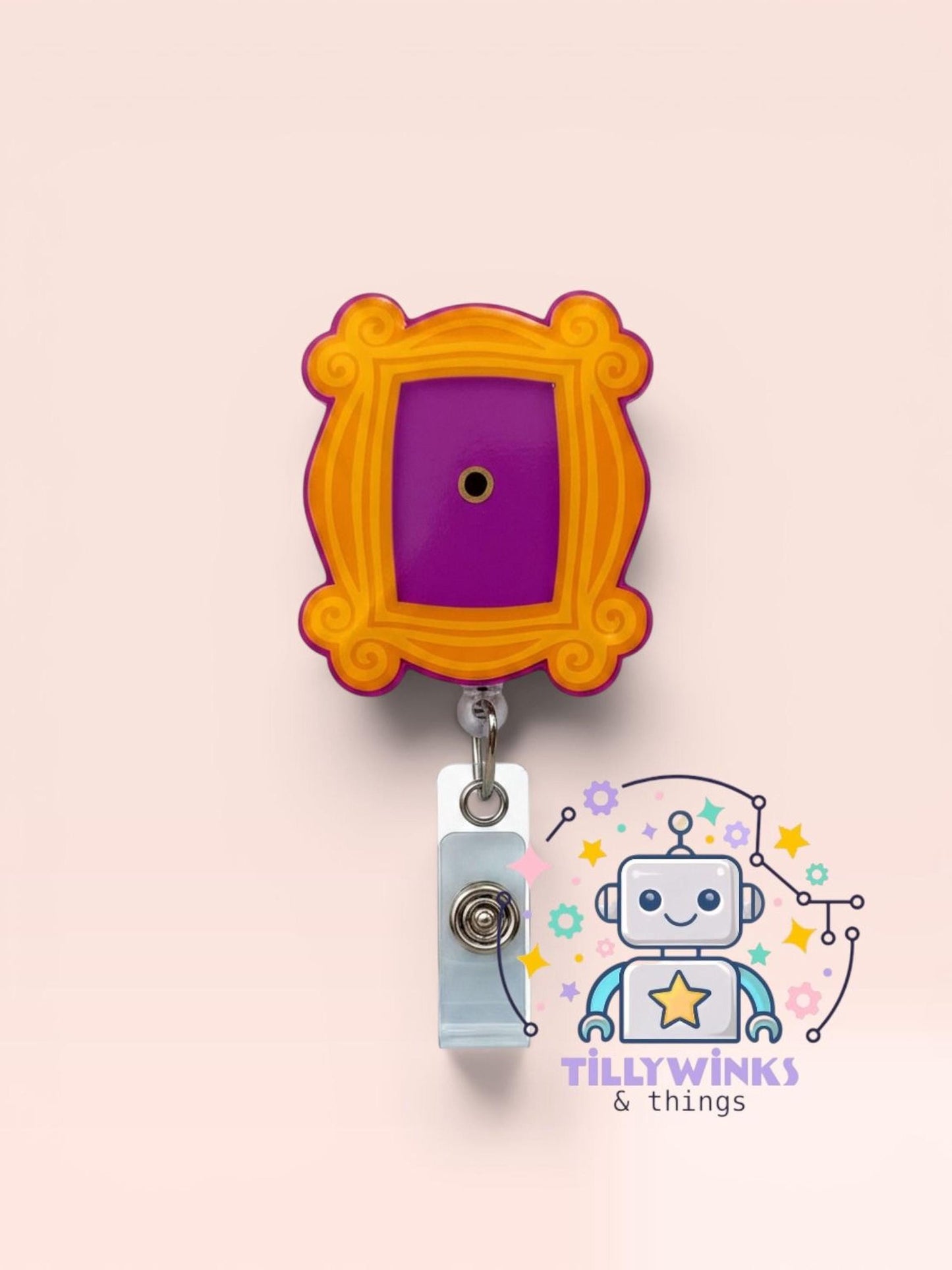 a colorful lanyard with a purple frame and an orange border, hanging on a light pink background. There is also a robot-like character with a star on its head, and the text "Tillywinks & things" is visible in the image.