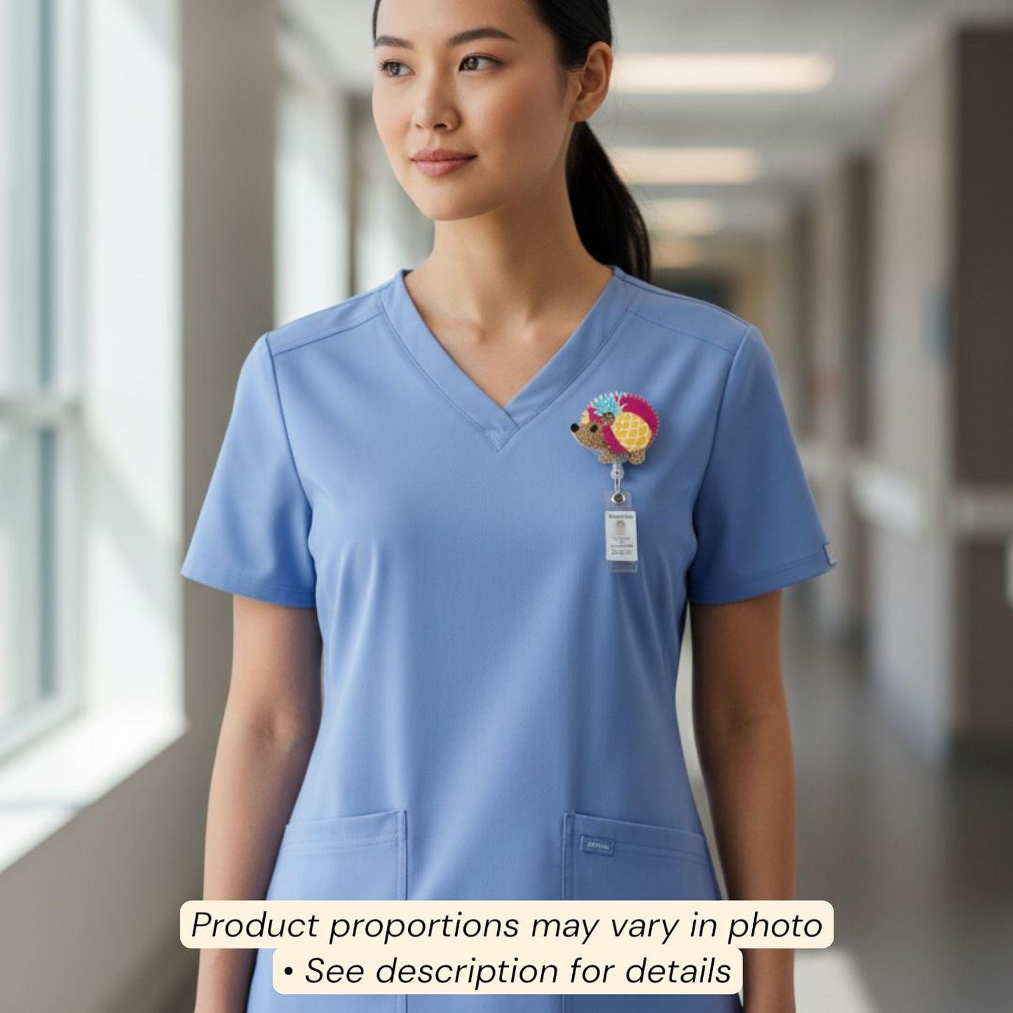 A woman wearing a blue medical uniform with a small, colorful charm on the left side of her chest.