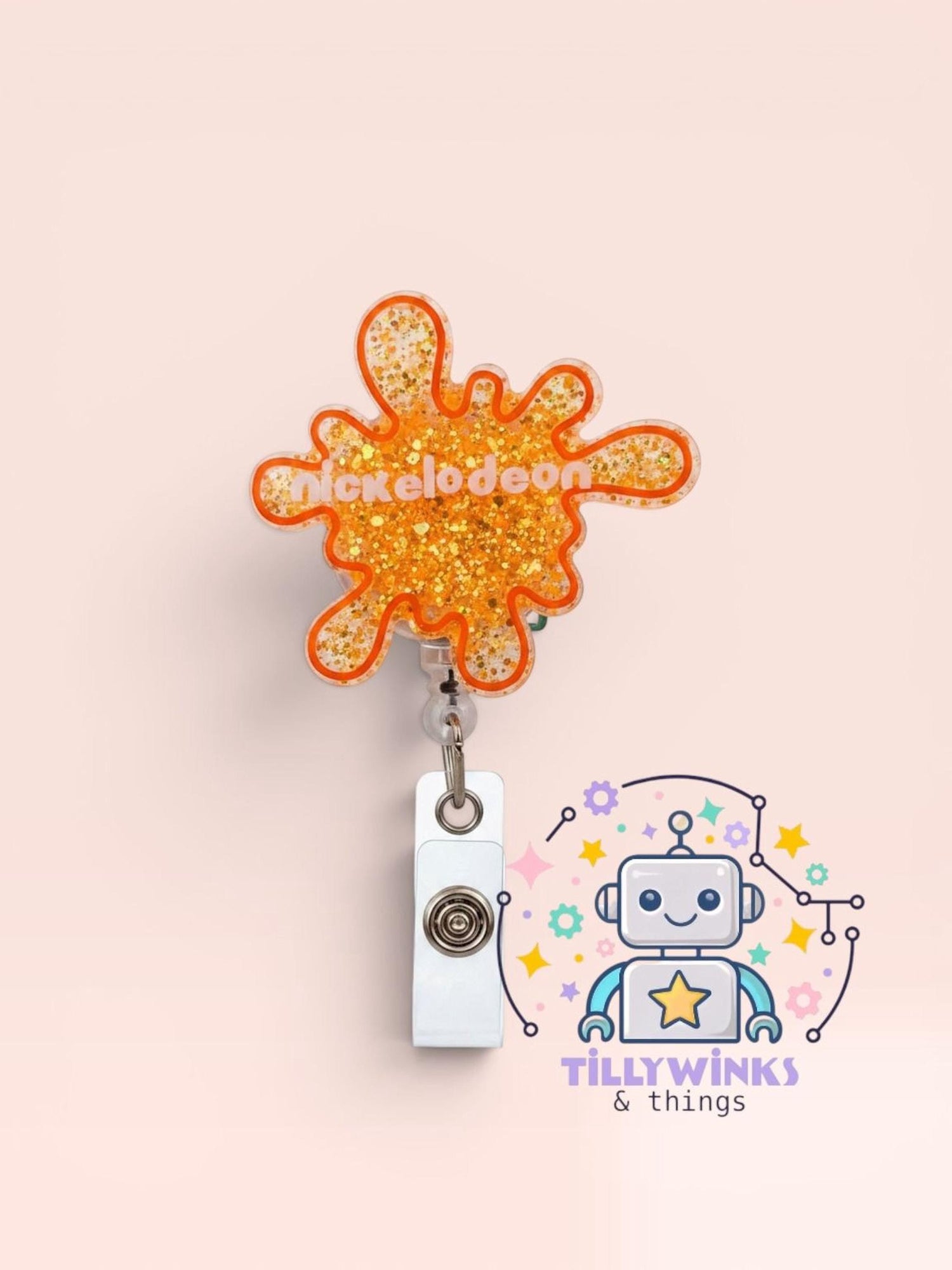 a bright orange glittery splash-shaped badge with the word " Nickelodeon" written on it, hanging on a wall. Below the badge, there is a logo for "Tillywinks & things", which appears to be a company or brand related to the image.