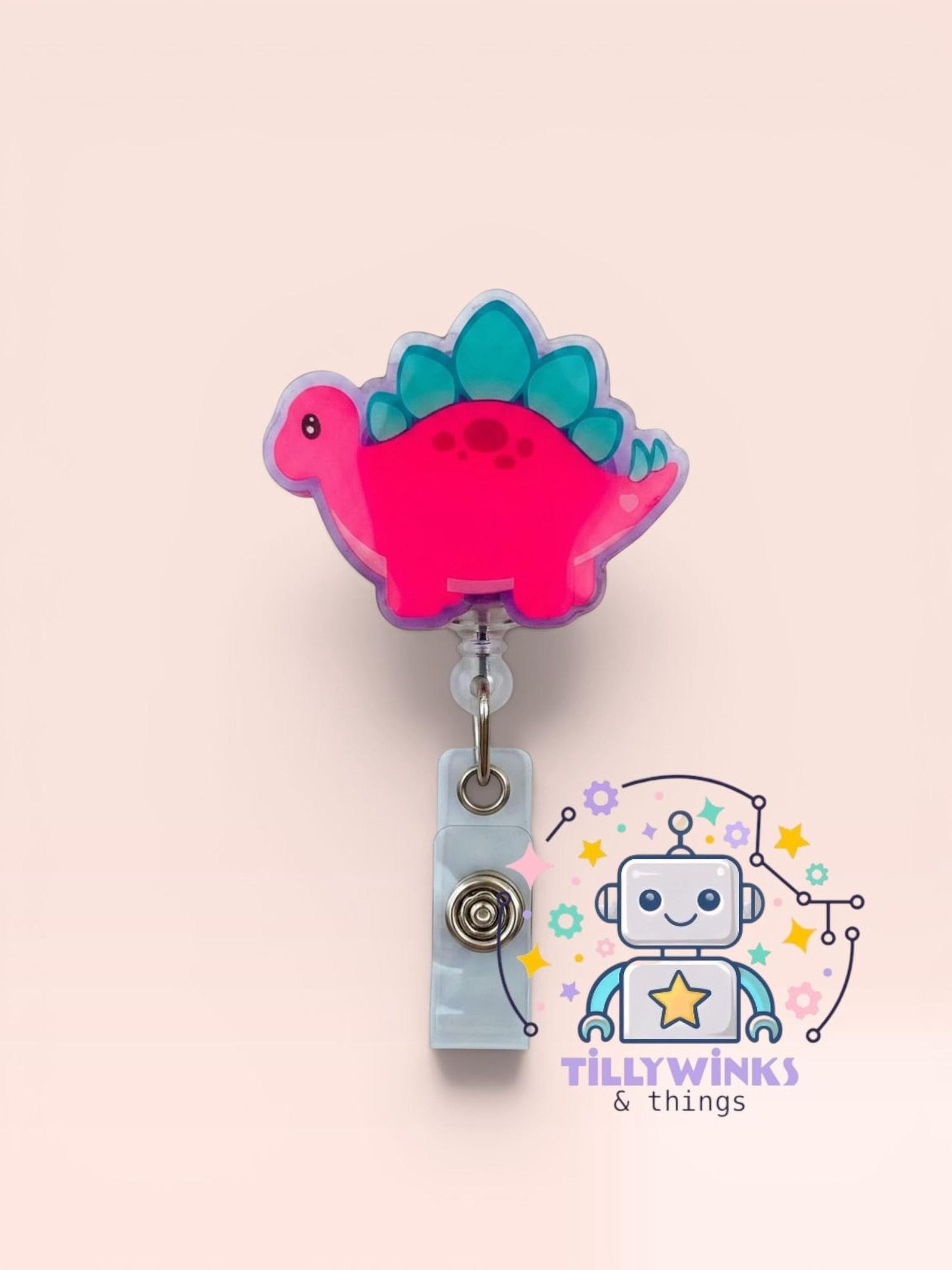 A pink dinosaur-shaped badge with a clear plastic holder attached to it, along with a robot-like character and various colorful elements.